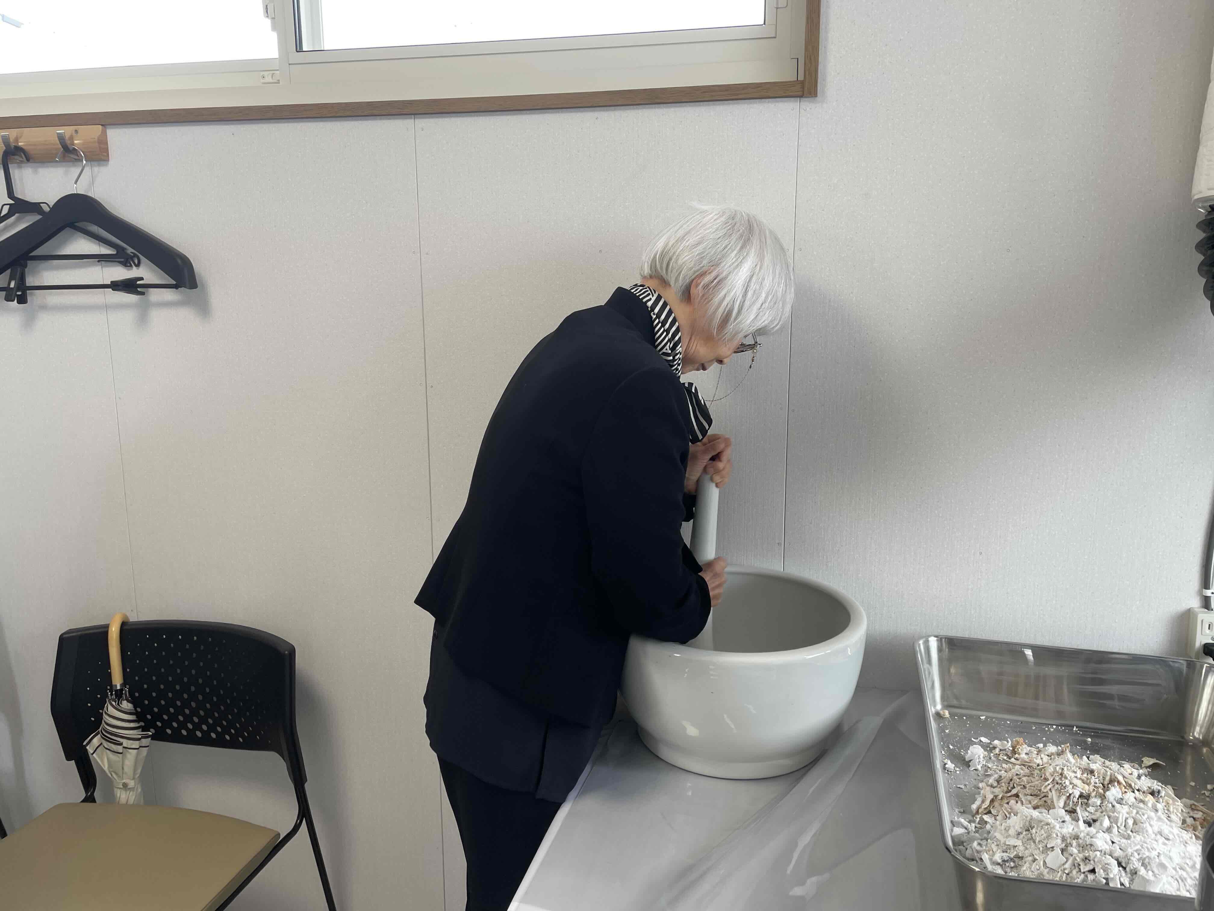 乳鉢と乳棒で遺骨を粉末化する様子